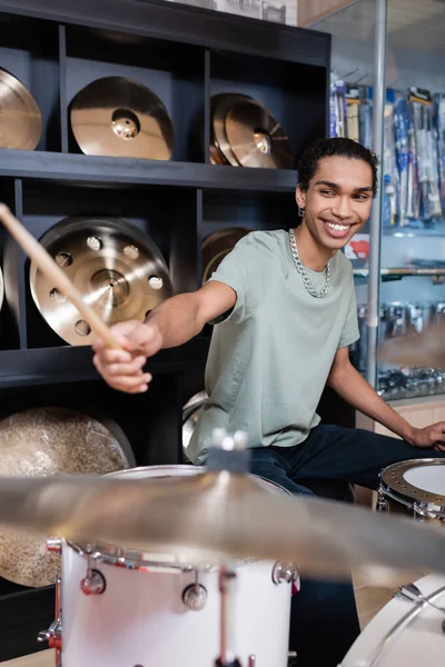 Lächelnder afrikanisch-amerikanischer Musiker spielt Schlagzeug im Musikladen — Stockfoto