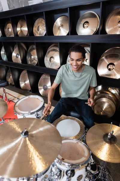 African american customer playing drums near plates in music store — Stock Photo