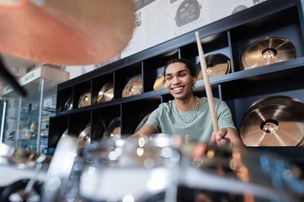 Lächelnder afrikanisch-amerikanischer Mann spielt verschwommenes Schlagzeug in Musikladen — Stockfoto