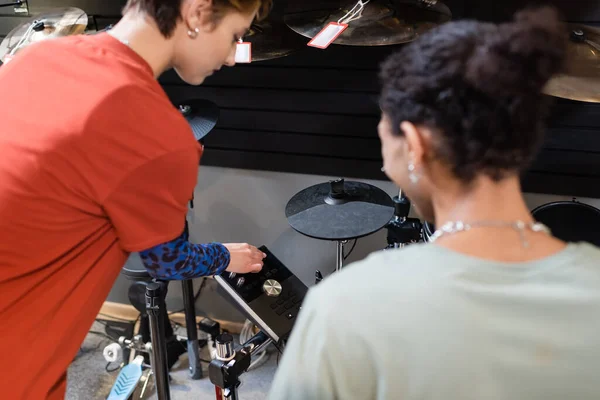Seller standing near electronic drum set and african american customer in music store — Stock Photo