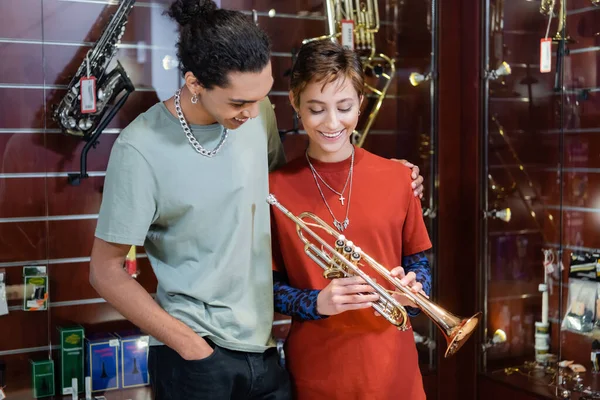 African american man hugging girlfriend with trumpet in music store — Photo de stock