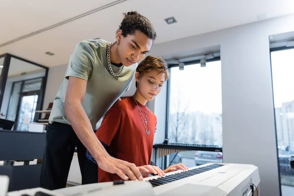 African american man playing synthesizer with girlfriend in music store — Stock Photo