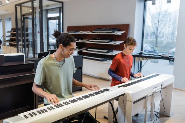 African american man performing synthesizer near girlfriend in music store — Stockfoto