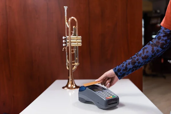 Cropped view of woman paying with credit card near trumpet in music shop — Foto stock