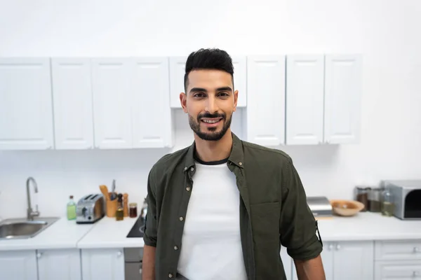 Улыбающийся арабиец смотрит в камеру на кухне — стоковое фото