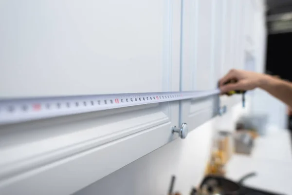 Cropped view of blurred man measuring cupboards in kitchen — Stock Photo