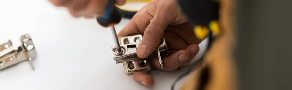 Cropped view of man screwing nail from hinge of cupboard at home, banner — Stockfoto