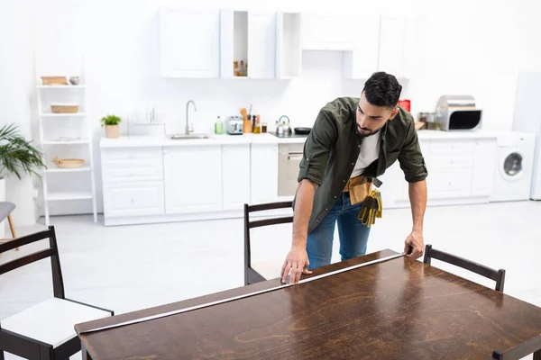 Young arabian carpenter measuring wooden table in kitchen — Fotografia de Stock