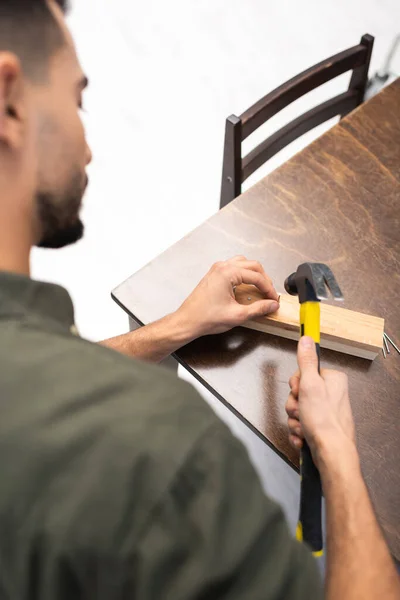 High angle view of muslim man knocking nail in wooden board at home - foto de stock