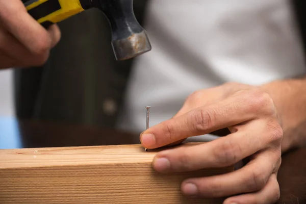 Cropped view of man holding nail and hammer near wooden board at home — Stock Photo