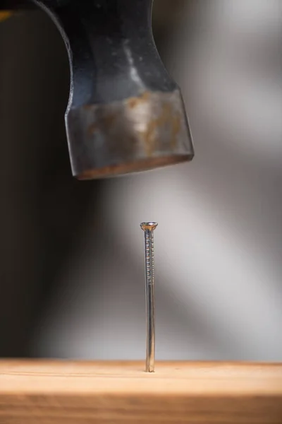 Close up view of hammer and nail in wooden board — Stock Photo