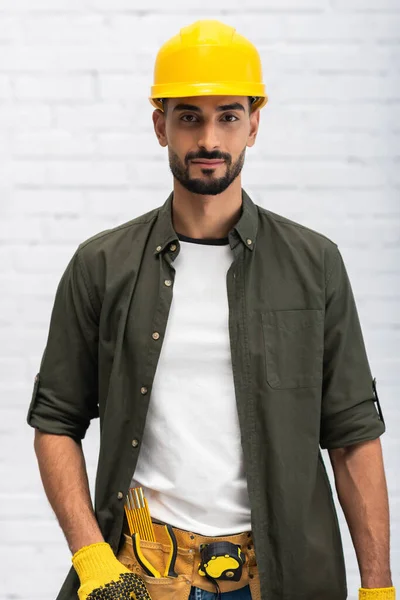 Young muslim craftsman in helmet holding toolbox and looking at camera at home — Stock Photo