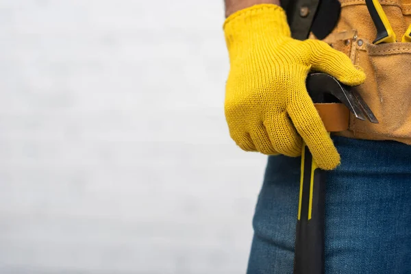 Cropped view of craftsman in glove holding hammer in tool belt at home - foto de stock