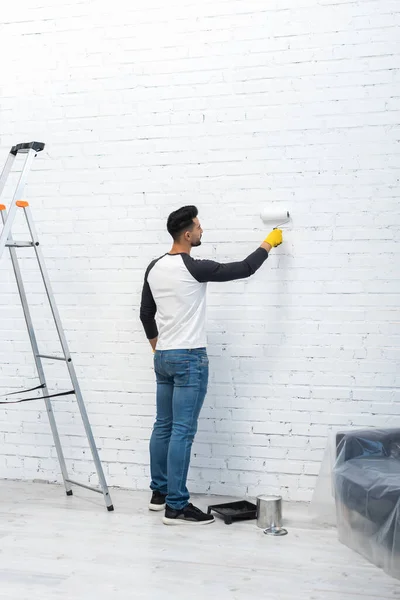 Side view of arabian man coloring wall near ladder at home — Photo de stock