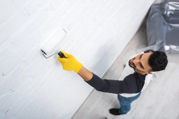 Overhead view of blurred muslim man coloring white brick wall at home — Foto stock