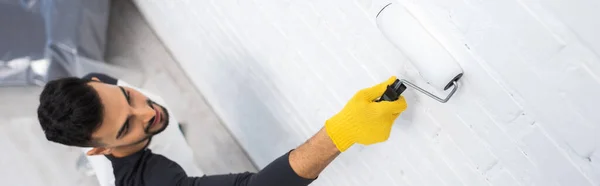 Overhead view of arabian man painting brick wall at home, banner - foto de stock