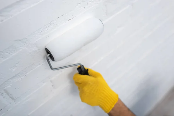 Cropped view of man in glove painting brick wall at home — Photo de stock