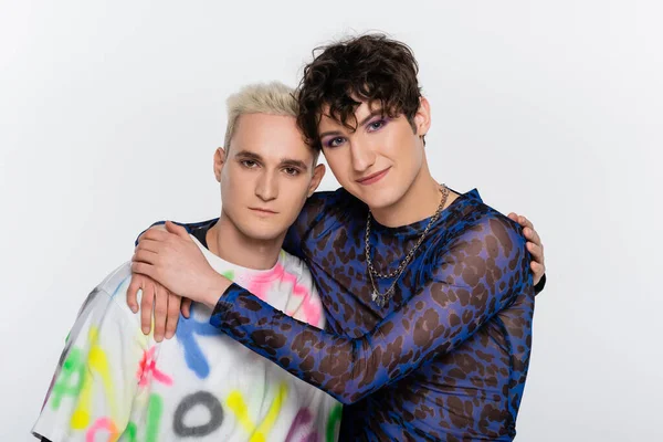 Smiling nonbinary person embracing gay man isolated on grey — стоковое фото