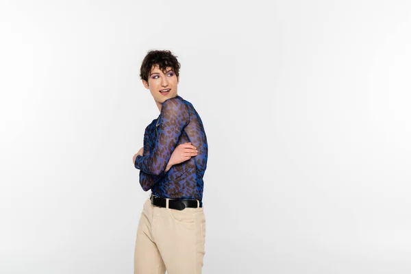 Smiling nonbinary person in stylish clothes standing with crossed arms and looking away isolated on grey — Photo de stock