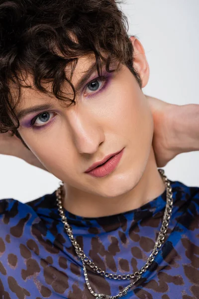 Close up portrait of young queer model with makeup looking at camera isolated on grey — стоковое фото