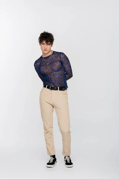 Full length of queer person in beige trousers and spotty long sleeve shirt on grey background — стоковое фото