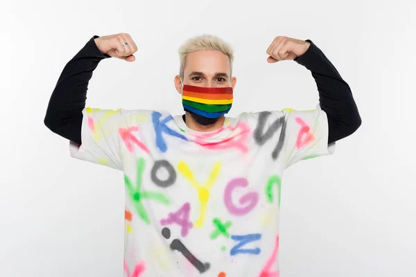 Gay man in rainbow colors medical mask demonstrating strength isolated on grey — Fotografia de Stock