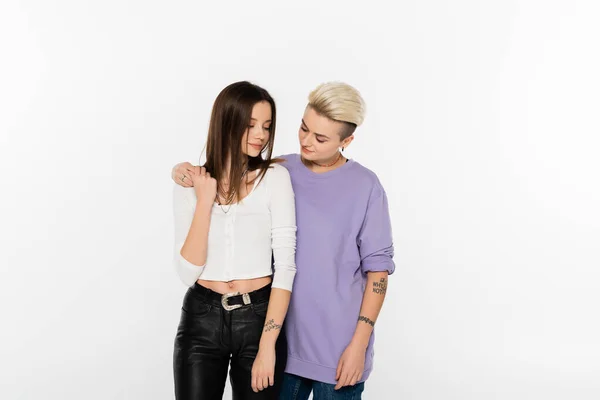 Young and stylish lesbian partners holding hands isolated on grey — стоковое фото