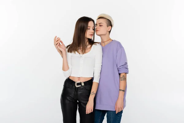 Young and trendy lesbian women holding hands isolated on grey — Stock Photo