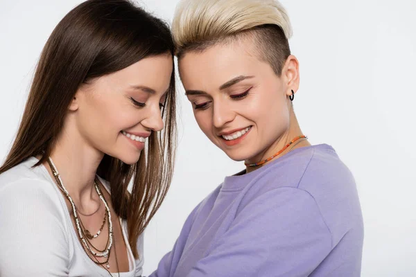 Happy lesbian woman in beads smiling near blonde girlfriend isolated on grey — Stockfoto