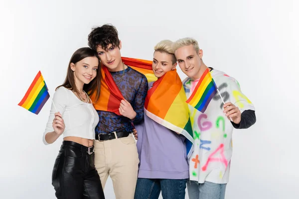 Young and trendy lgbtq community friends standing with rainbow flags isolated on grey - foto de stock