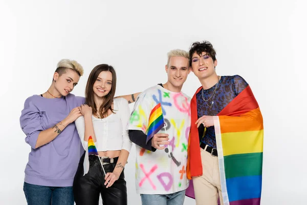 Happy and stylish lgbtq community people with rainbow flags smiling at camera isolated on grey — Stockfoto