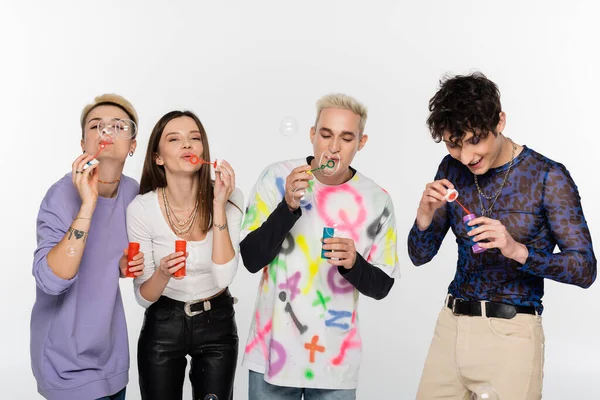 Young lgbtq community people blowing soap bubbles isolated on grey — Stock Photo
