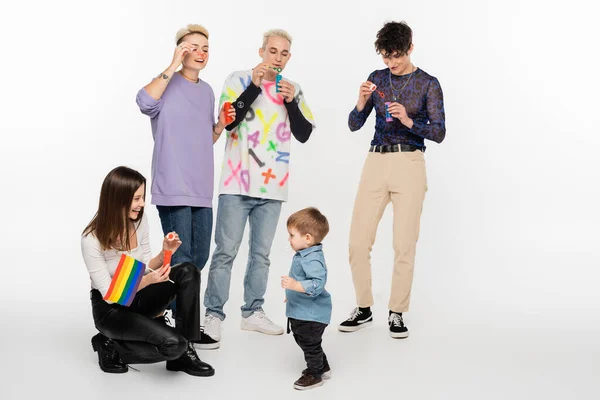 Happy lesbian woman with rainbow flag near toddler boy and lgbtq community friends on grey background — Photo de stock