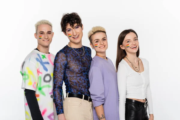 Smiling lgbtq community friends with rainbow flags on faces looking at camera isolated on grey — Foto stock