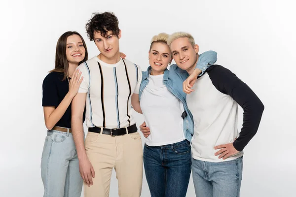 Young friends in fashionable clothing smiling at camera isolated on grey — Stock Photo