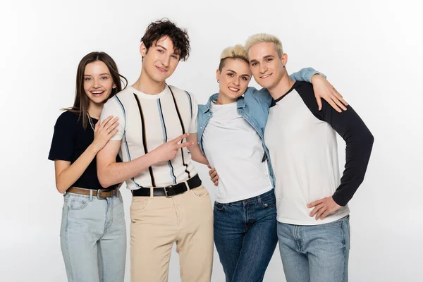 Young man showing peace gesture near stylish friends embracing isolated on grey — Stock Photo