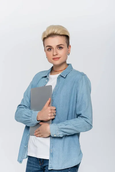 Young and stylish woman with laptop looking at camera isolated on grey — Stock Photo