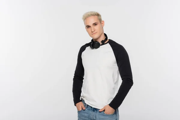 Trendy man in black and white long sleeve shirt posing with hands in pockets isolated on grey — Stockfoto