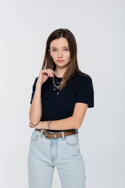 Brunette woman in black t-shirt standing with hand near face isolated on grey - foto de stock