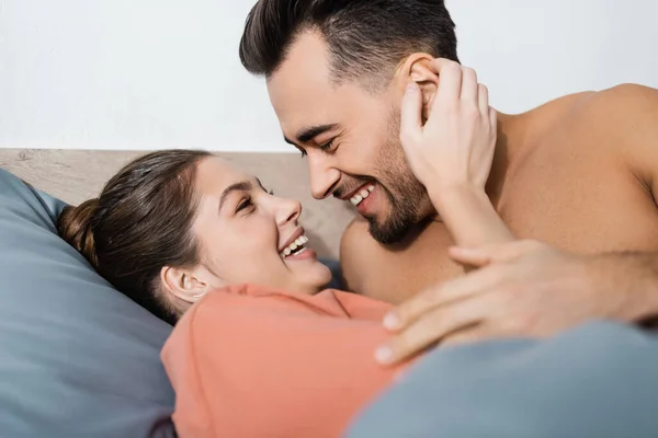 Щаслива молода пара посміхається один одному на ліжку вдома — стокове фото
