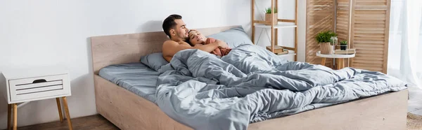 Молодая женщина спит рядом мужчина обнимает ее под серым одеялом, баннер — стоковое фото