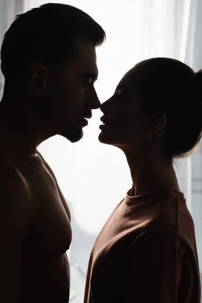 Sagome scure di donna in t-shirt e uomo senza camicia in piedi faccia a faccia e guardarsi l'un l'altro — Foto stock