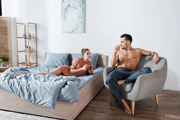 Young couple looking at each other while drinking tea in modern bedroom — Stock Photo