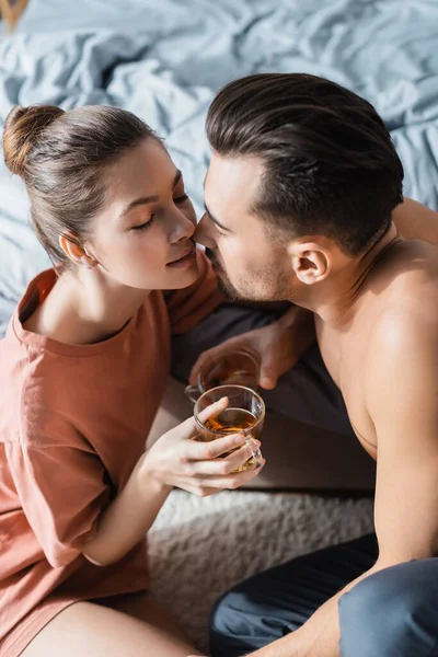 Ângulo alto vista do casal no amor segurando xícaras de chá e beijando com os olhos fechados — Fotografia de Stock