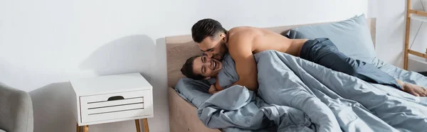 Giovane uomo senza maglietta che abbraccia donna felice su biancheria da letto grigia, banner — Foto stock