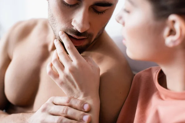 Blurred woman touching lips of shirtless and sexy boyfriend — Stock Photo