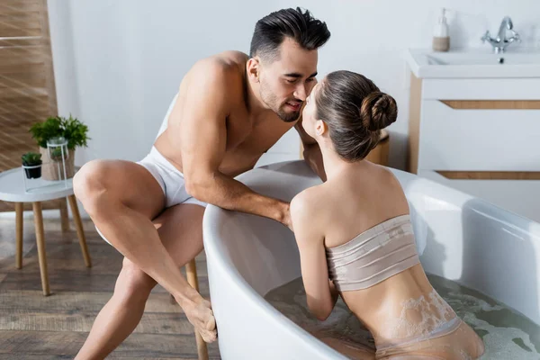 Giovane donna in bagno e senza maglietta uomo in mutande guardando l'un l'altro faccia a faccia — Foto stock