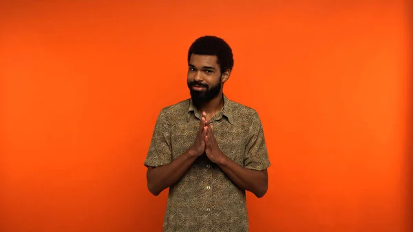 Homem americano africano astuto com barba olhando para a câmera enquanto gesticulando no fundo laranja — Fotografia de Stock