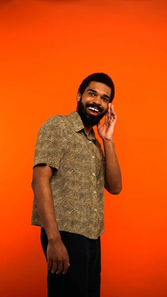 Vista vertical del joven afroamericano excitado con barba en naranja - foto de stock