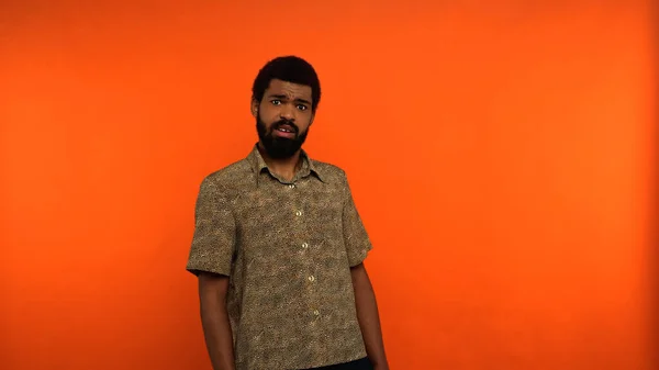 Displeased african american man with beard looking at camera on orange background — Stock Photo